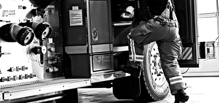 black and white photo of fireman getting into truck